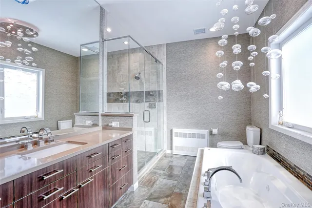 a spacious bathroom with a granite countertop double vanity sink a mirror and a bathtub