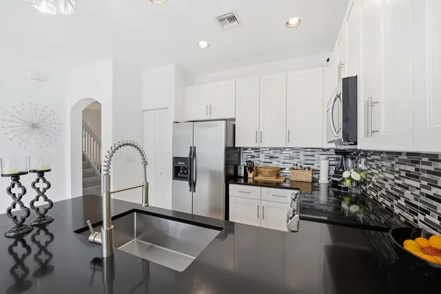 a kitchen with stainless steel appliances granite countertop a refrigerator and a stove top oven