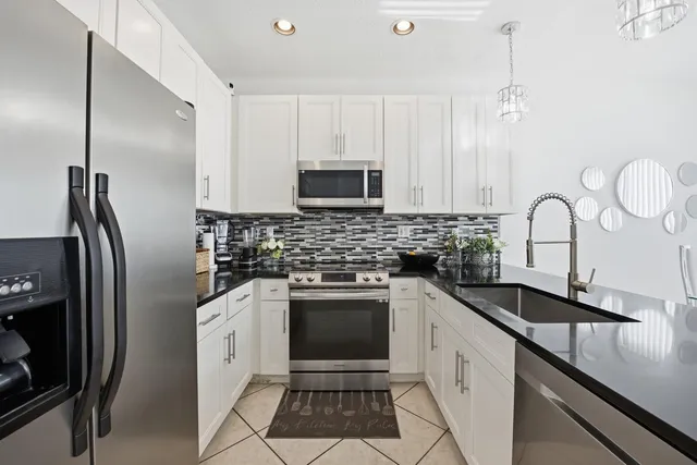 a kitchen with kitchen island granite countertop a sink appliances and cabinets