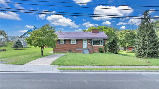 a front view of a house with a garden and trees