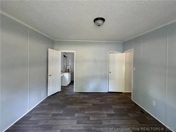 a view of a hallway with wooden floor and a bathroom