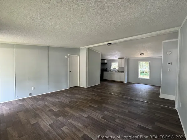 a view of an empty room with window and wooden floor