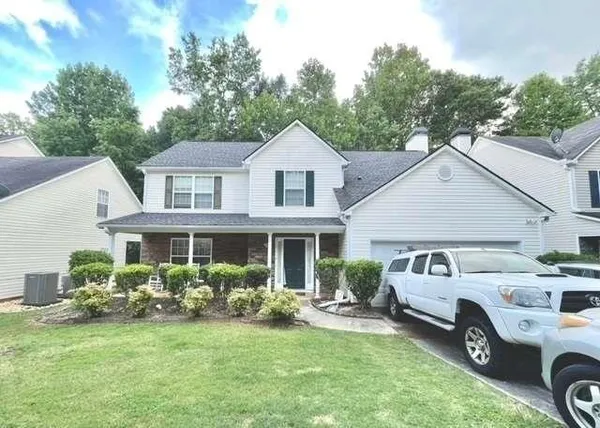a front view of a house with a garden and trees