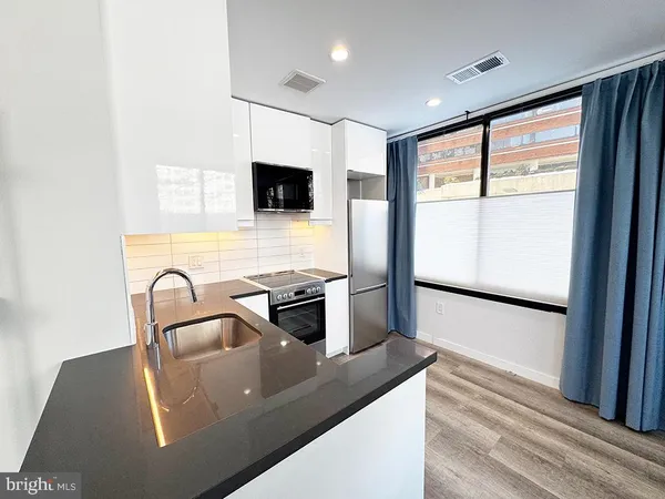 a kitchen with stainless steel appliances granite countertop a refrigerator a sink dishwasher a stove and a microwave oven on granite countertops