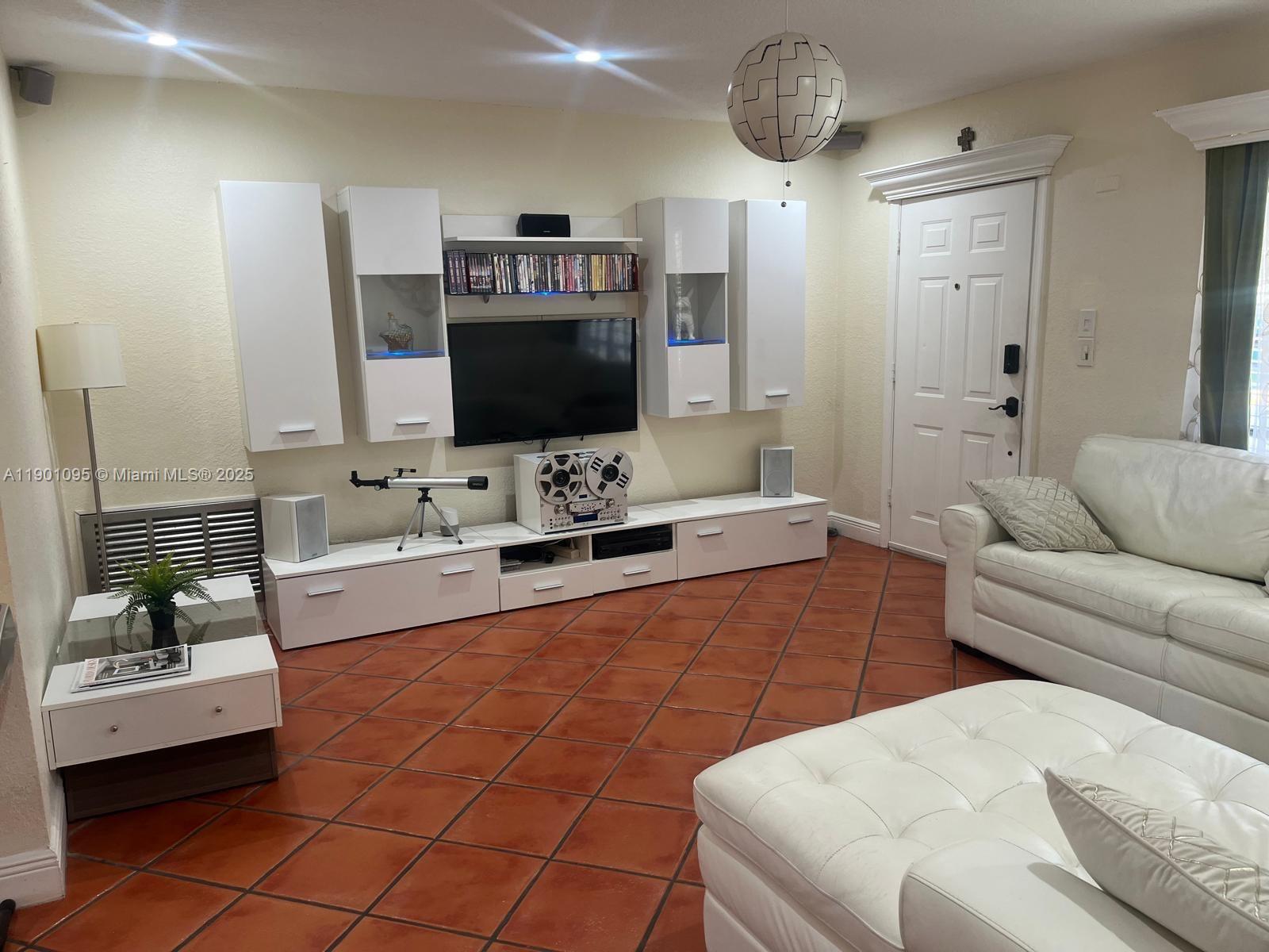 4913 Northwest 47th Avenue, Unit 4913 Tamarac, FL 33319 - Photo 2 of 7 a living room with furniture and a flat screen tv
