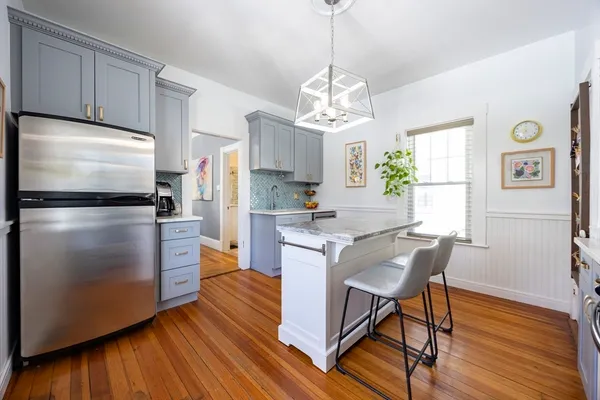 a kitchen with stainless steel appliances granite countertop a refrigerator a stove a sink dishwasher and a dining table with wooden floor