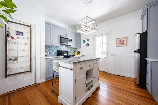 a kitchen with stainless steel appliances granite countertop a refrigerator a stove a microwave oven a sink and dishwasher with wooden floor