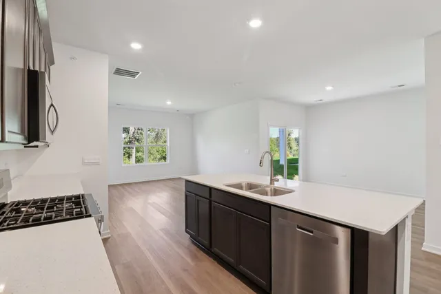 a kitchen with stainless steel appliances a sink stove and wooden floor