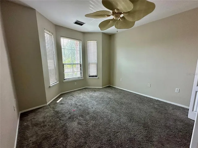 an empty room with windows and fan