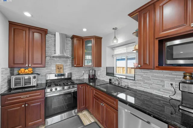 a kitchen with stainless steel appliances granite countertop a stove sink and cabinets