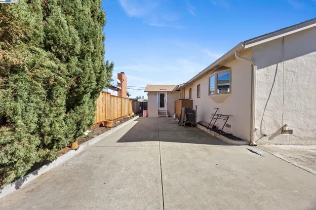 a view of a backyard house with plants and wooden fence