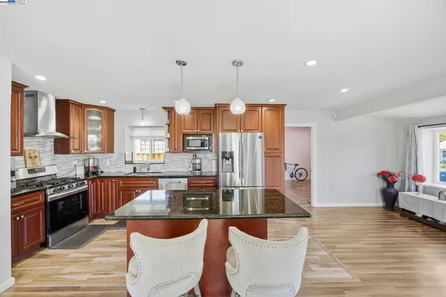 a large kitchen with stainless steel appliances granite countertop a stove and a granite counter tops with white cabinets