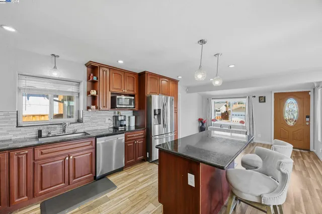 a kitchen with stainless steel appliances granite countertop a kitchen island hardwood floor sink stove dining table and chairs