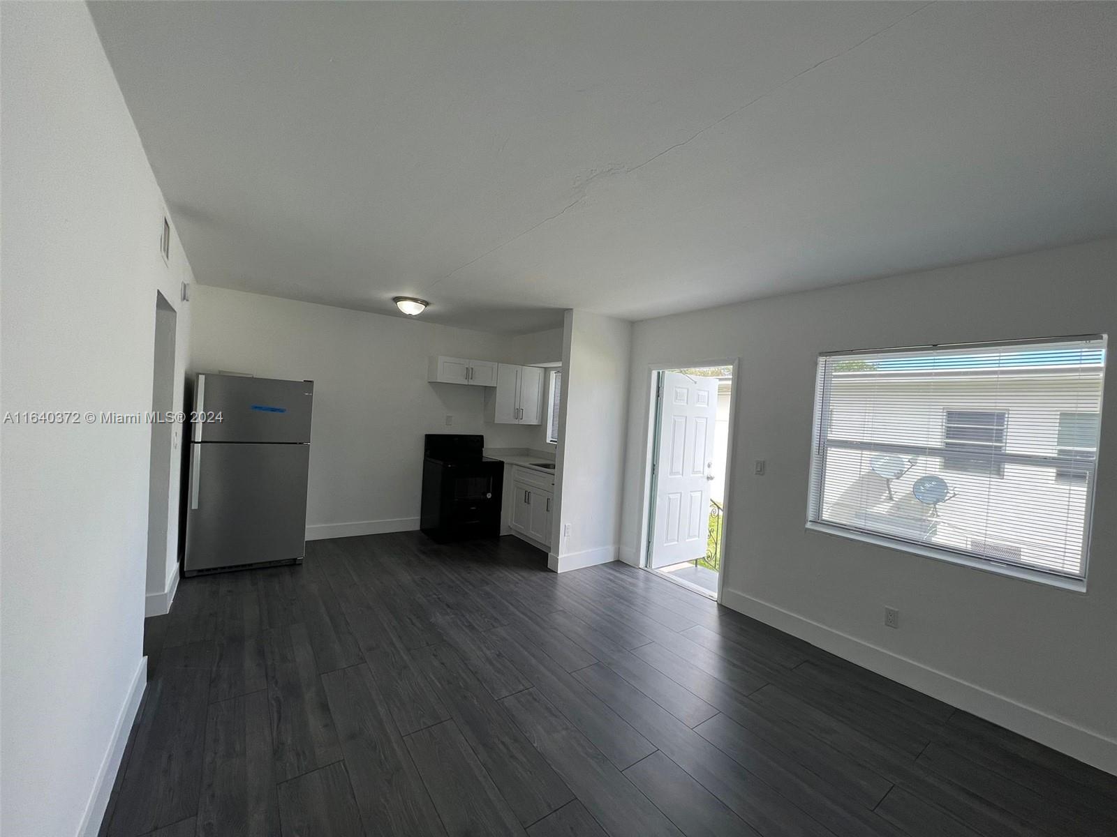 2150 Northwest 24th Street Miami, FL 33142 - Photo 11 of 18 an empty room with wooden floor kitchen view and a window