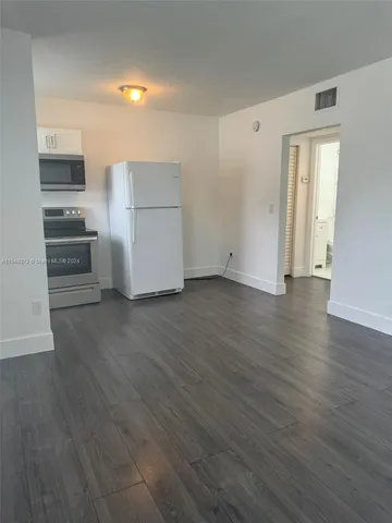 a view of a kitchen with wooden floor and electronic appliances