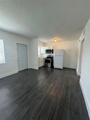 a view of empty room with wooden floor and window