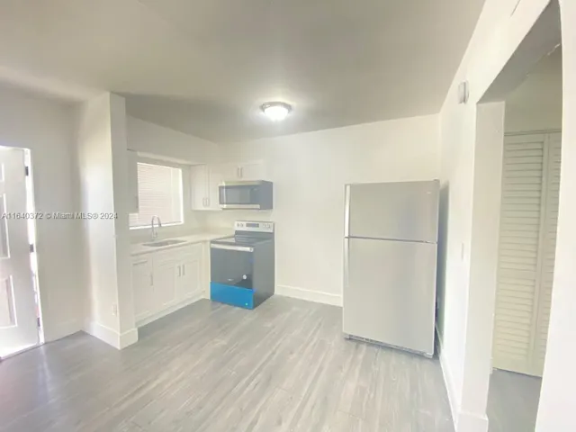 a kitchen with a refrigerator a sink and dishwasher with wooden floor