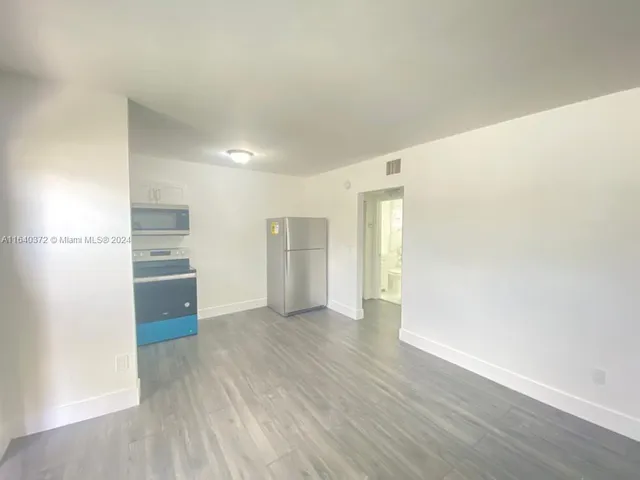 a view of a kitchen with wooden floor and a refrigerator