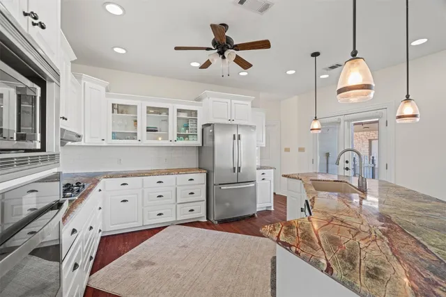 a kitchen with stainless steel appliances granite countertop a stove refrigerator a oven with a dining table and chairs with wooden floor