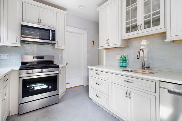 a kitchen with stainless steel appliances granite countertop grey cabinets a stove a sink and dishwasher