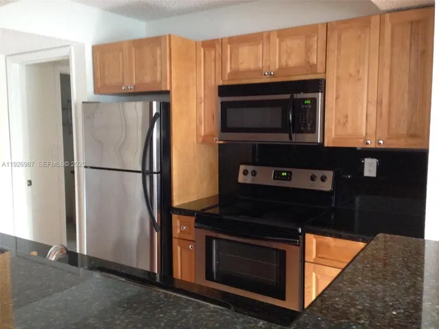 a kitchen with granite countertop wooden cabinets and a stove top oven