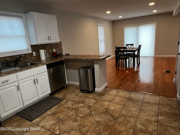 a kitchen with granite countertop a stove a sink a dining table and chairs