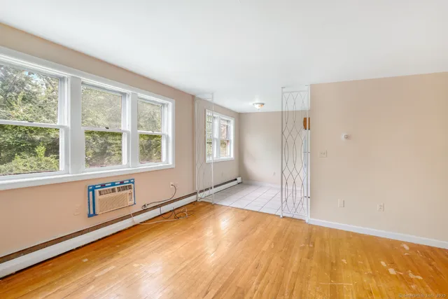 a view of an empty room with window and wooden floor
