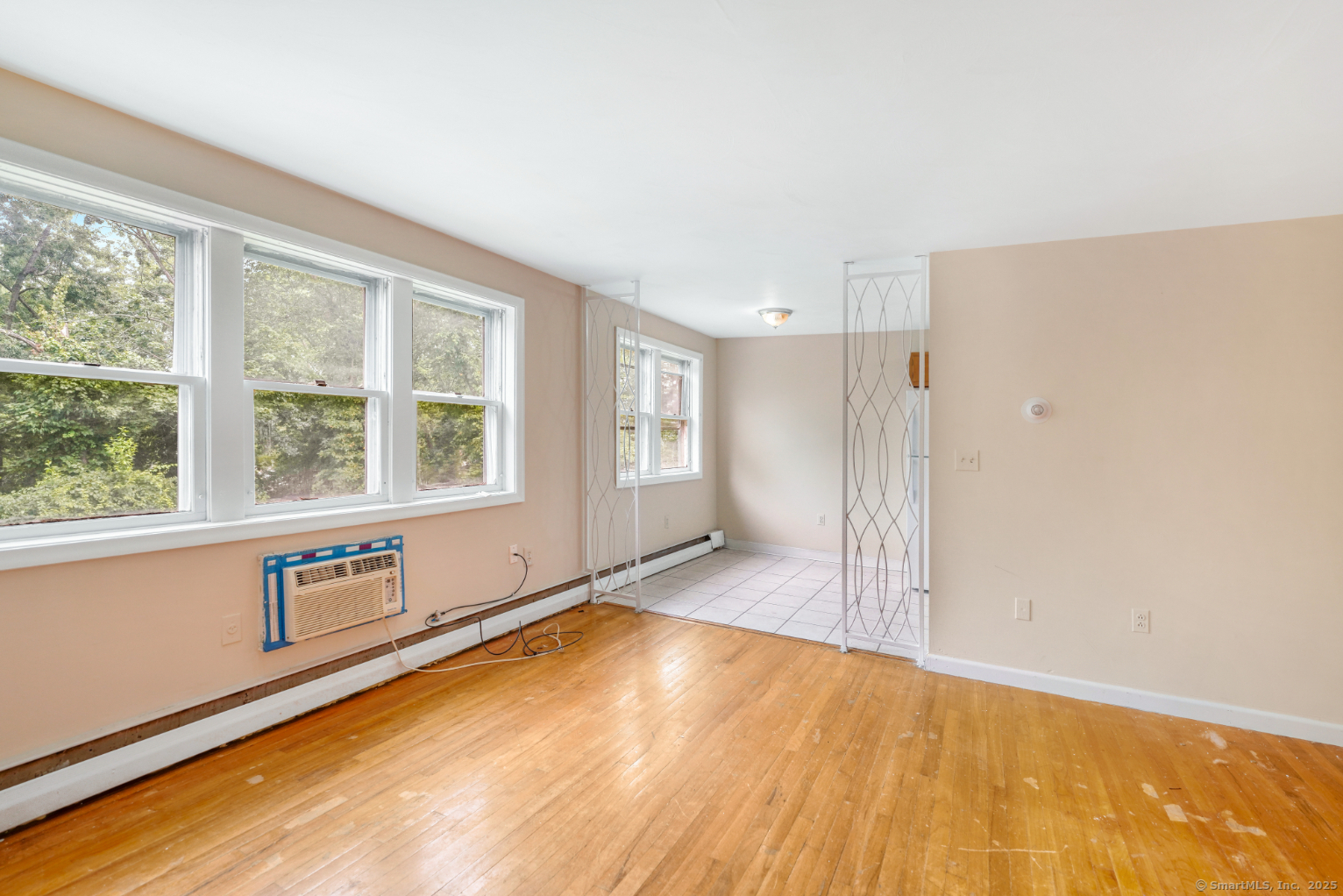 a view of an empty room with window and wooden floor