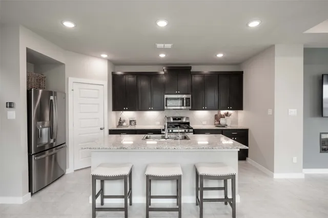 a kitchen with stainless steel appliances granite countertop a kitchen island hardwood floor and a sink