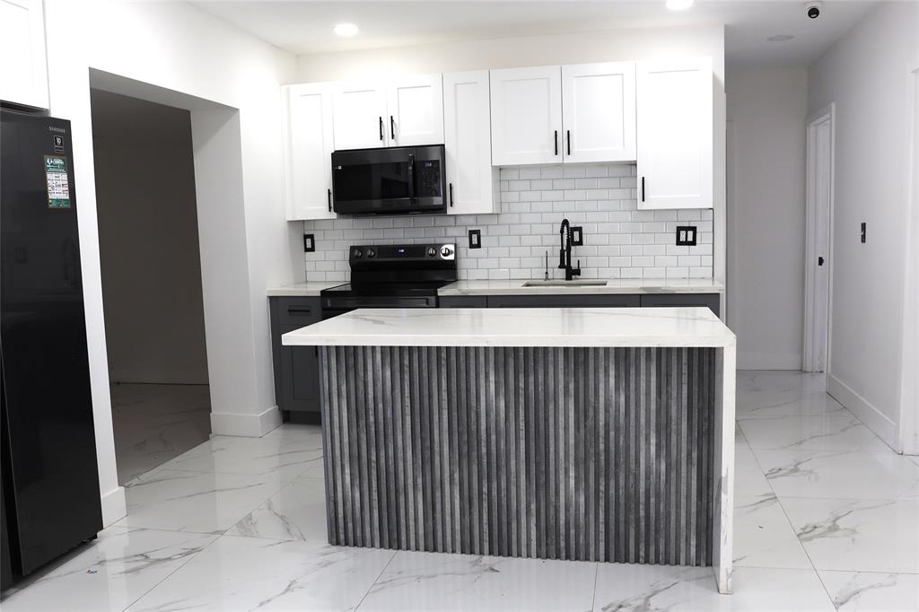 3075 Northwest 68th Street Miami, FL 33147 - Photo 4 of 24 a kitchen with stainless steel appliances kitchen island granite countertop a refrigerator and a stove top oven