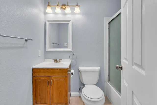 a bathroom with a toilet sink vanity and mirror