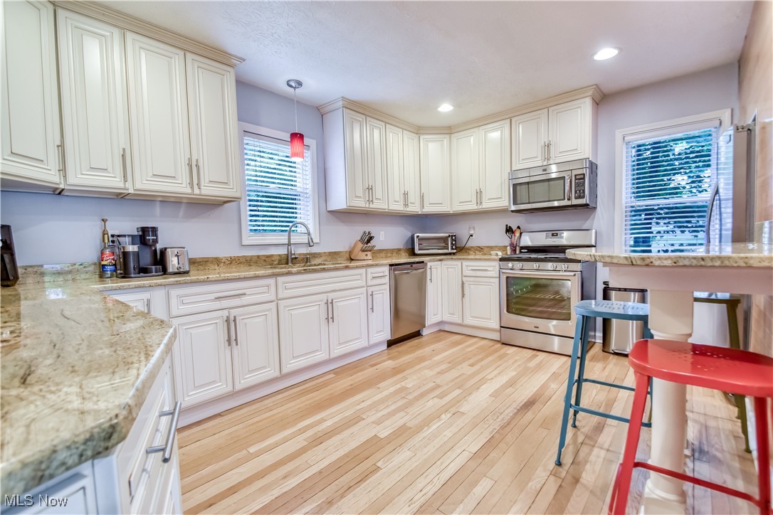 8115 Stockbridge Road Mentor, OH 44060 - Photo 13 of 46 Kitchen with stainless steel appliances, light wood-style floors, hanging light fixtures, recessed lighting, and white cabinets
