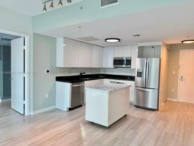 a living room with kitchen island granite countertop wooden floor and a sink