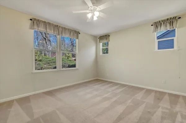 a view of an empty room with window and chandelier fan