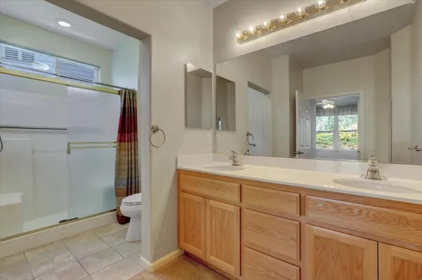 a bathroom with a double vanity sink mirror and toilet