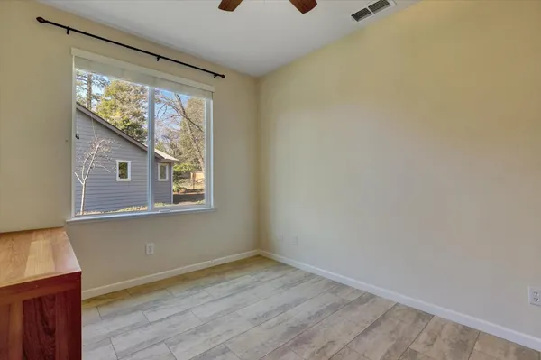 a view of an empty room with wooden floor and windows
