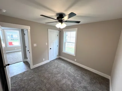 an empty room with windows and fan