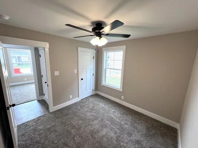 an empty room with windows and fan