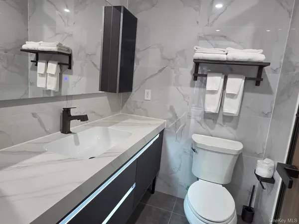 a bathroom with a granite countertop toilet sink and mirror