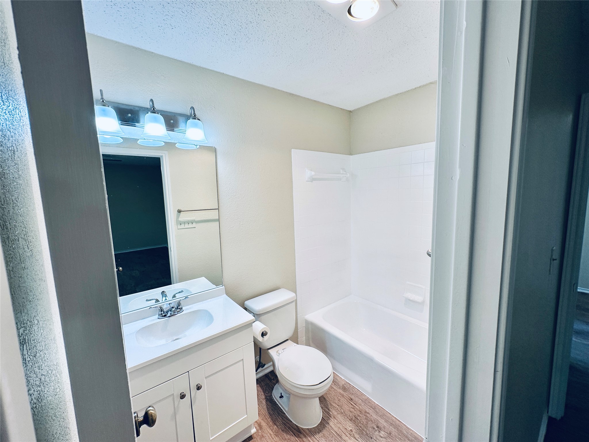 379 Fantail Loop, Unit B Austin, TX 78734 - Photo 29 of 33 A classic bathroom layout includes a vanity sink and tub shower combo with wood-look flooring.