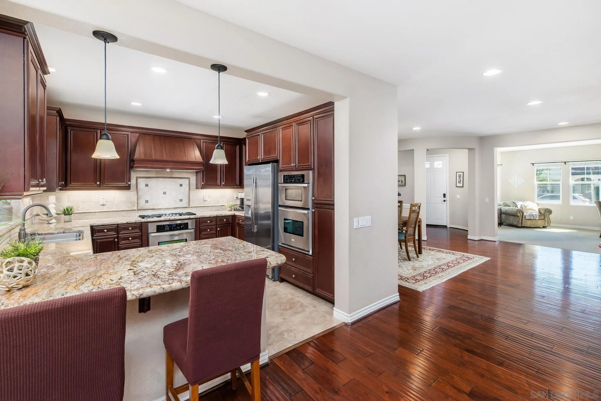 650 Liquid Amber Way San Marcos, CA 92078 - Photo 12 of 48 a kitchen with stainless steel appliances granite countertop a refrigerator a stove top oven a sink dishwasher and white cabinets with wooden floor