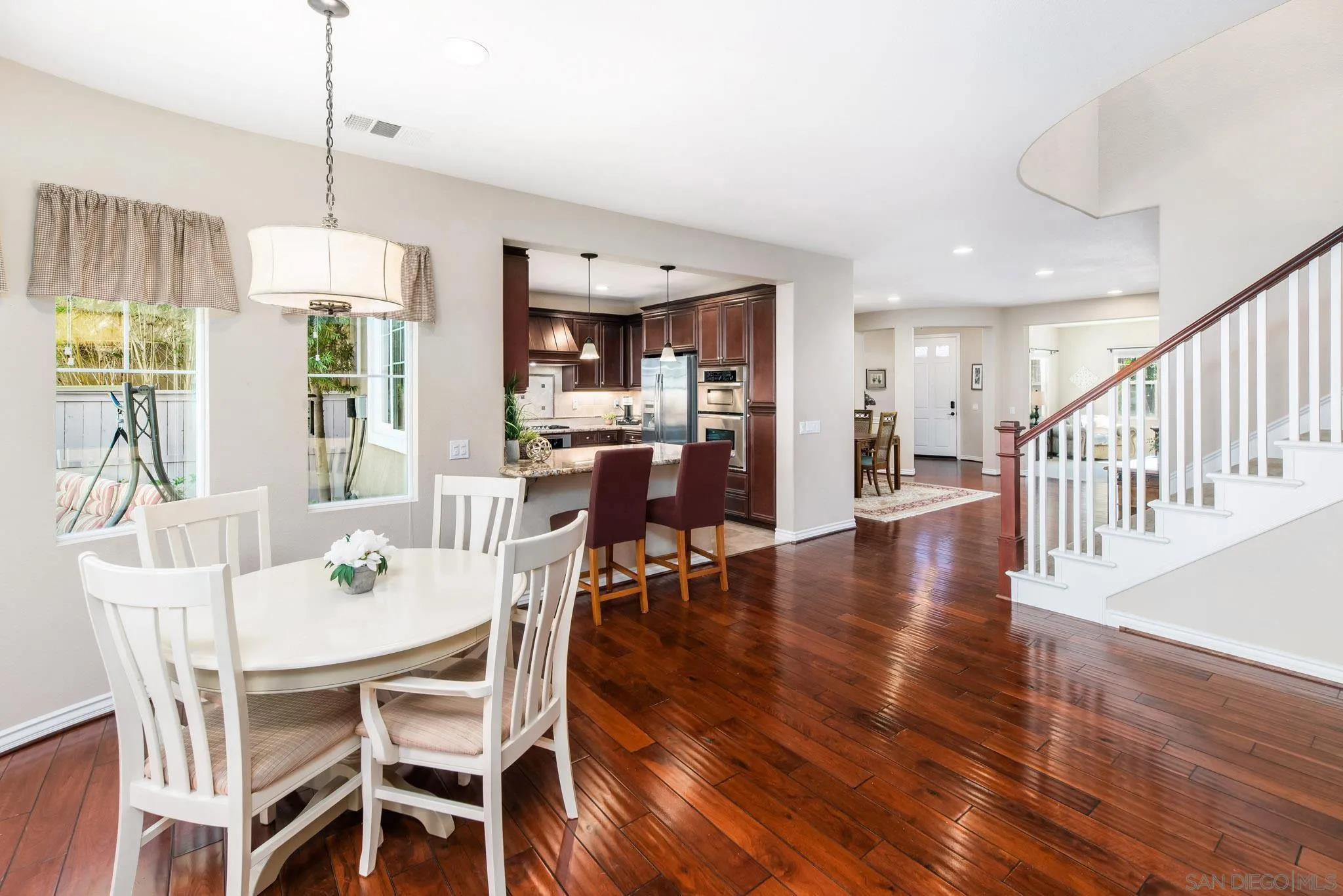 650 Liquid Amber Way San Marcos, CA 92078 - Photo 21 of 48 a dining room with wooden floor a chandelier a glass table and chairs