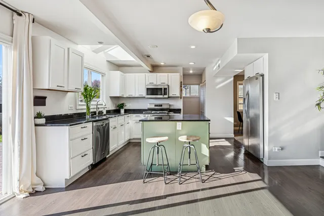 a kitchen with stainless steel appliances granite countertop a refrigerator a stove and a sink