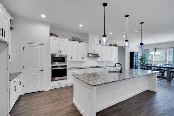 a kitchen with stainless steel appliances granite countertop a sink a stove and a wooden floor