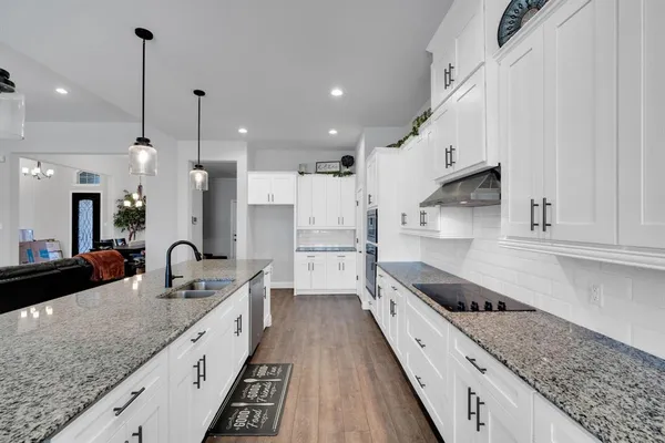 a kitchen with granite countertop a sink a counter top space stainless steel appliances and cabinets