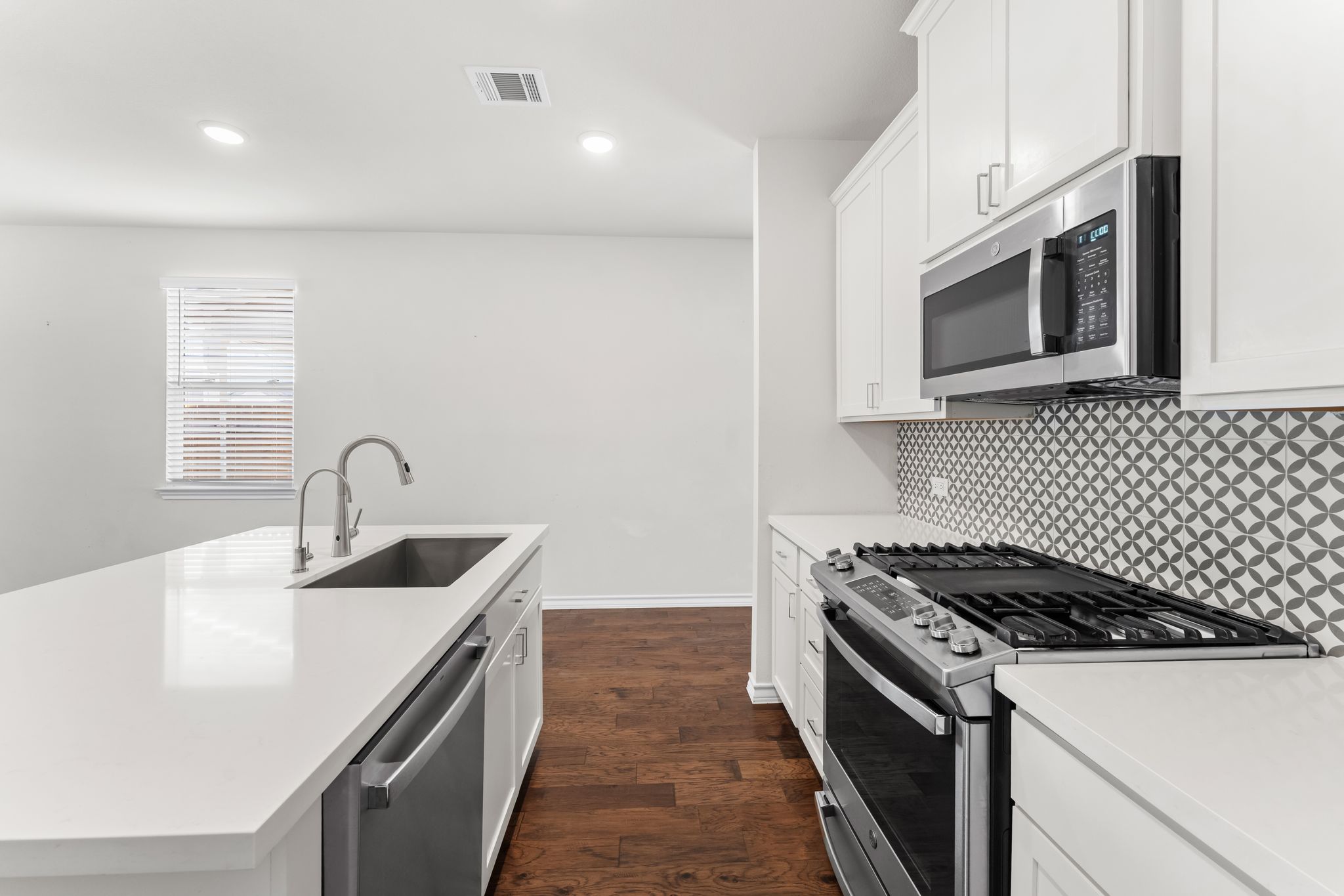 2803 Mary Elizabeth Drive Austin, TX 78728 - Photo 6 of 30 Kitchen featuring stainless steel appliances, white cabinets, dark wood-type flooring, recessed lighting, and a center island with sink