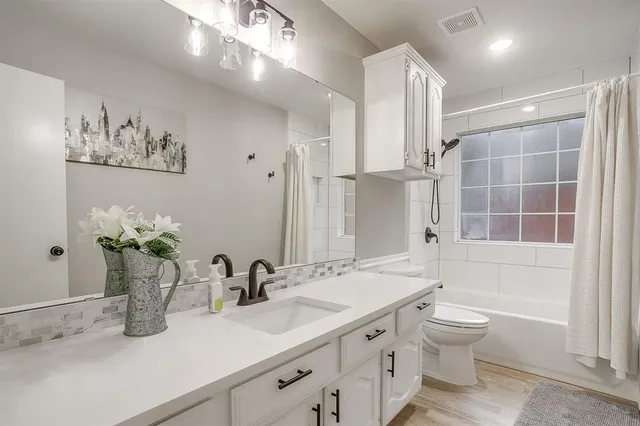 a bathroom with a granite countertop sink a toilet and shower
