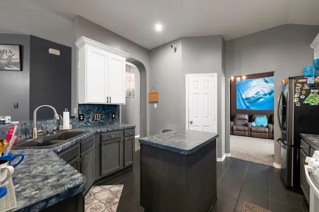 a kitchen with granite countertop a stove a sink dishwasher and a refrigerator with wooden floor