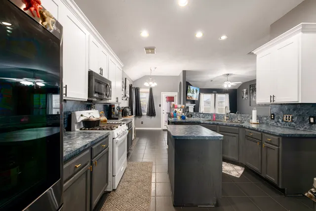 a kitchen with stainless steel appliances granite countertop a sink a stove and a refrigerator