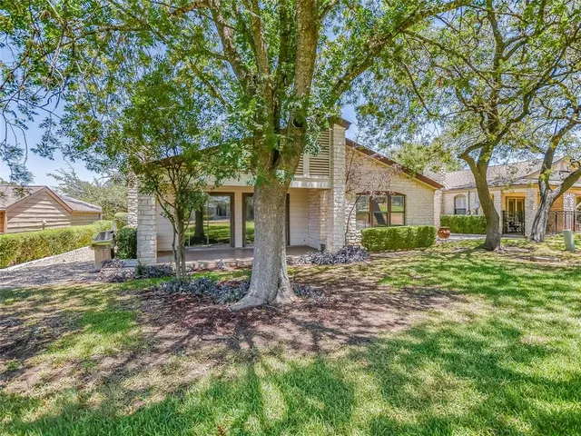 a view of a house with a yard and large tree